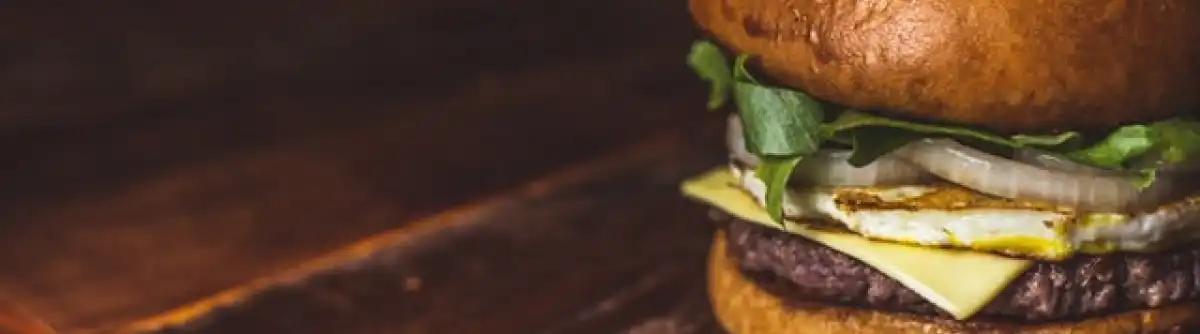 A burger with lettuce, onion, egg, and cheese.